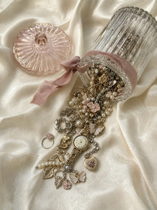 Jewellery spilling out of an open mystery jar onto cream silk