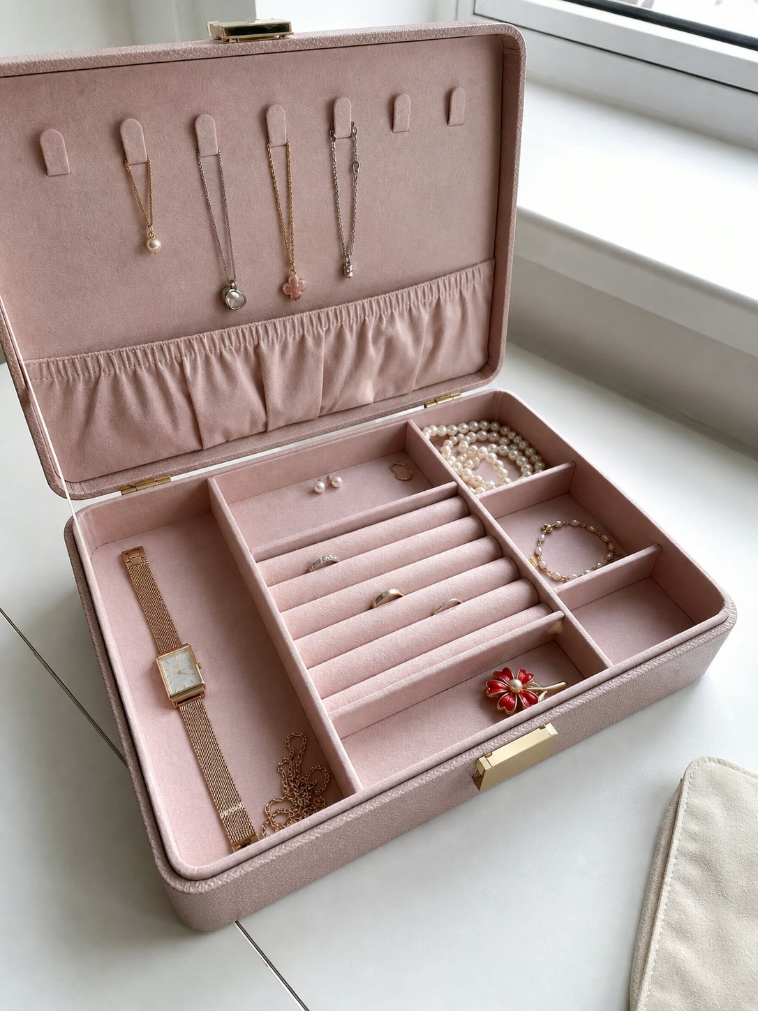 Open pink velvet jewellery box with ring slots and compartments